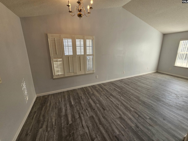 spare room featuring vaulted ceiling, dark wood-type flooring, a textured ceiling, and a chandelier