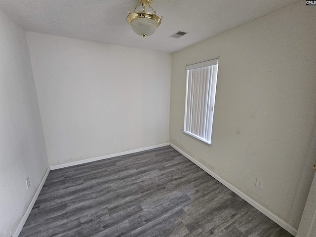 spare room with dark hardwood / wood-style floors and a textured ceiling