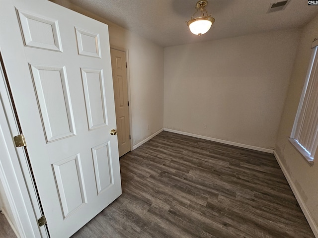 spare room featuring dark hardwood / wood-style flooring and a textured ceiling