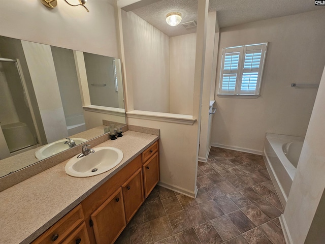 bathroom featuring vanity, a bath, and a textured ceiling