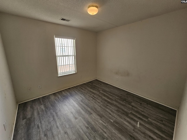 empty room featuring dark hardwood / wood-style floors and a textured ceiling