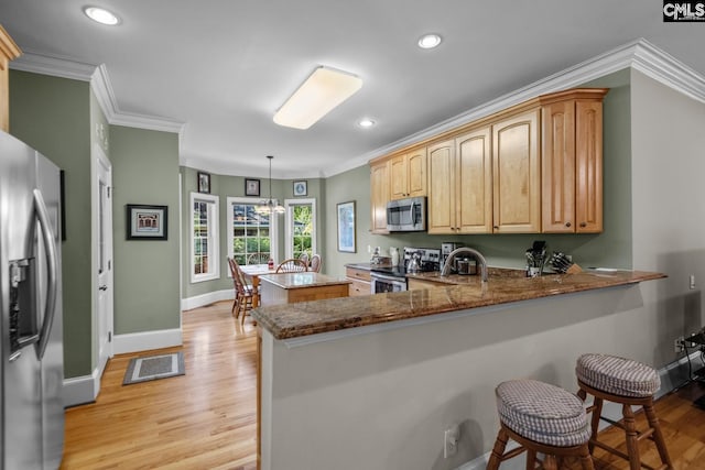 kitchen with appliances with stainless steel finishes, decorative light fixtures, stone countertops, and kitchen peninsula