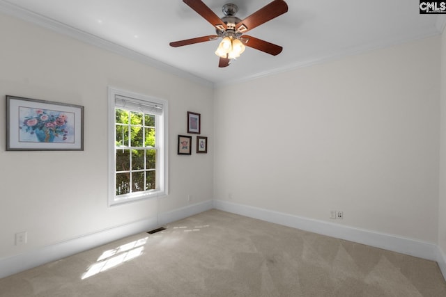 empty room featuring crown molding, light colored carpet, and ceiling fan