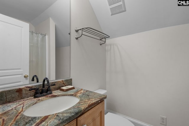 bathroom featuring vanity, lofted ceiling, and toilet