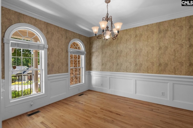 unfurnished dining area featuring a notable chandelier, wood-type flooring, and ornamental molding