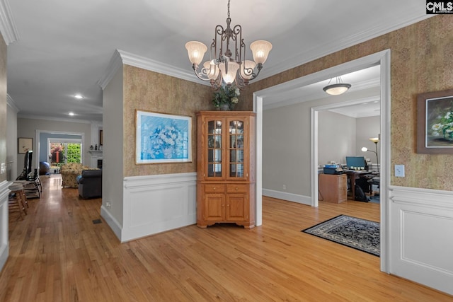 dining room with a notable chandelier, crown molding, and light hardwood / wood-style flooring