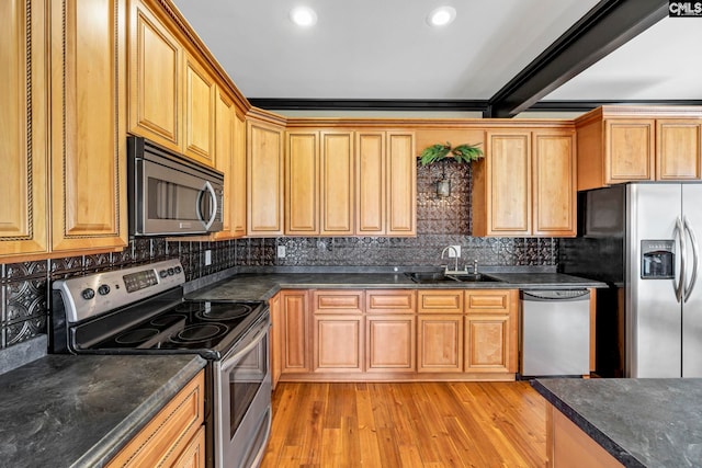 kitchen featuring tasteful backsplash, sink, light hardwood / wood-style flooring, and appliances with stainless steel finishes