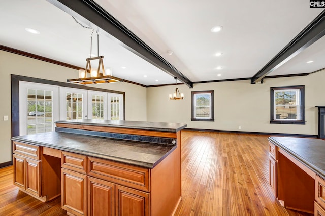 kitchen featuring pendant lighting, beam ceiling, a center island, and a wealth of natural light