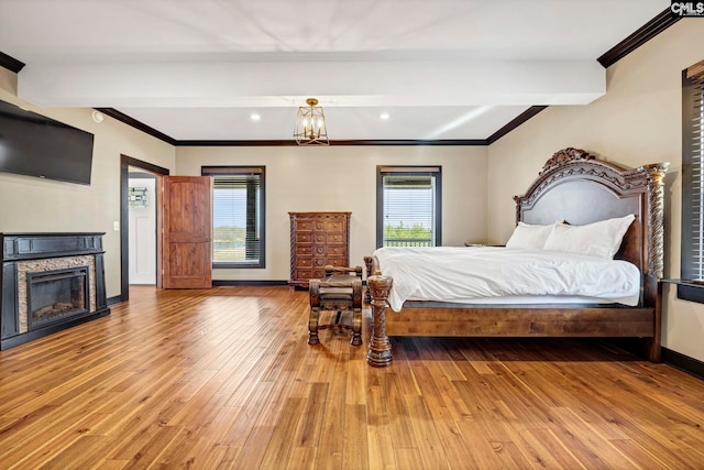 bedroom with crown molding, beam ceiling, a fireplace, and light wood-type flooring