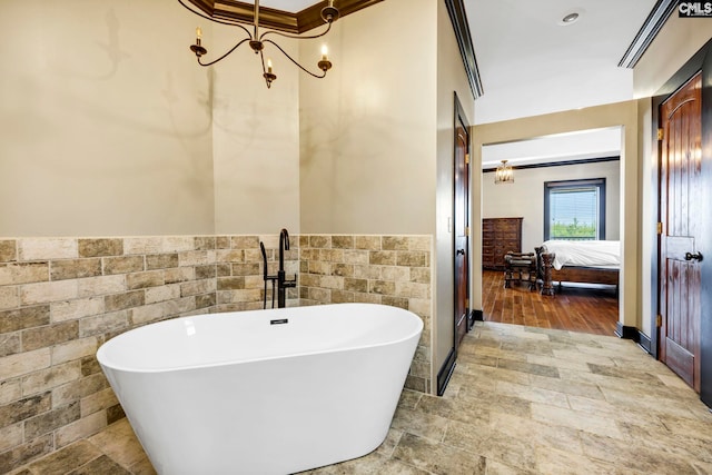 bathroom featuring an inviting chandelier, a bath, and tile walls