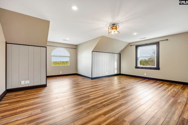 bonus room featuring lofted ceiling, plenty of natural light, and light wood-type flooring