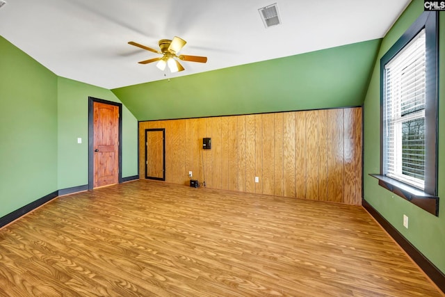 bonus room with ceiling fan, lofted ceiling, light hardwood / wood-style floors, and wood walls