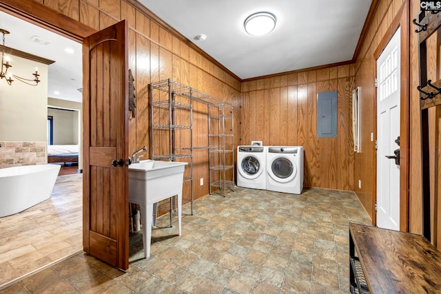 clothes washing area with crown molding, washer and dryer, electric panel, and wooden walls