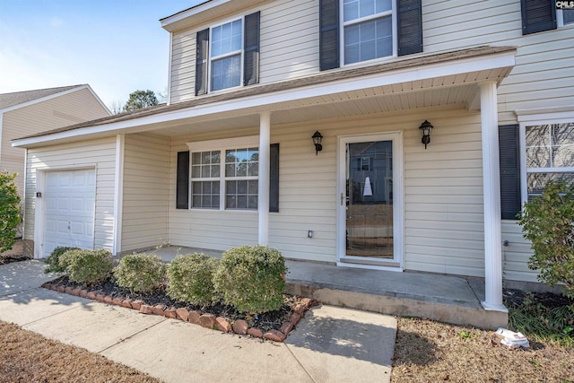 view of exterior entry featuring a garage and a porch