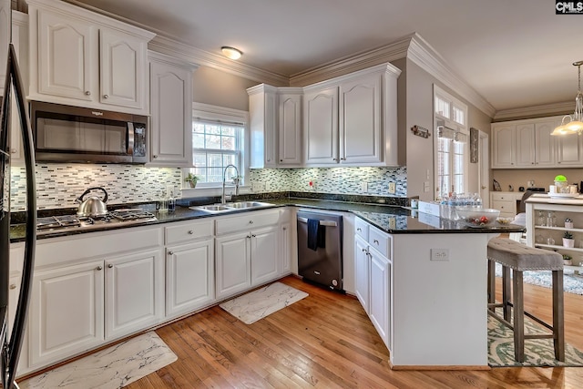 kitchen featuring sink, white cabinetry, appliances with stainless steel finishes, kitchen peninsula, and pendant lighting