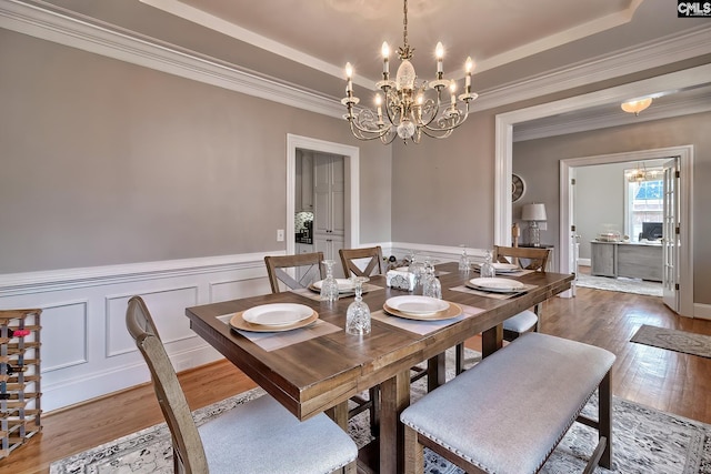 dining room featuring hardwood / wood-style flooring, crown molding, a raised ceiling, and a chandelier