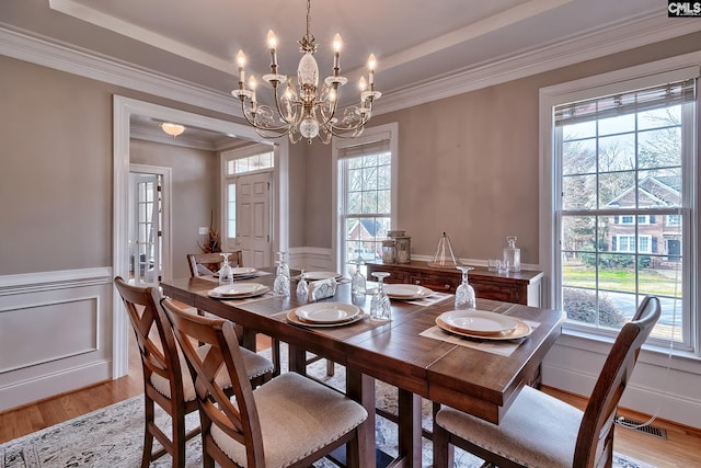 dining space with ornamental molding, a chandelier, and light wood-type flooring