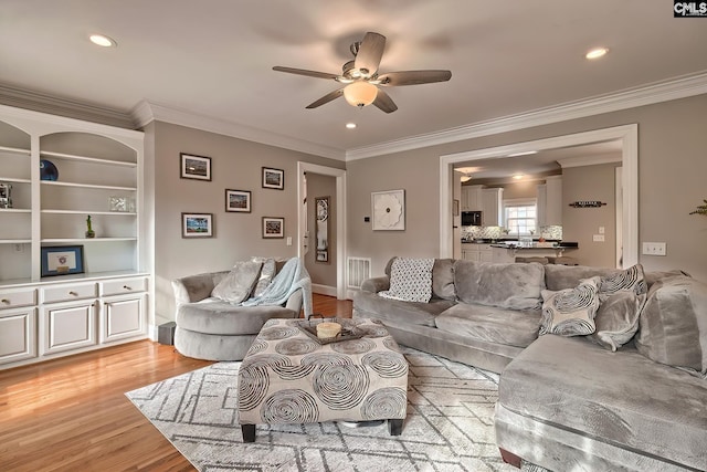 living room with crown molding, light hardwood / wood-style flooring, and ceiling fan