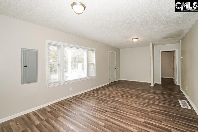 spare room with dark wood-type flooring, electric panel, and a textured ceiling