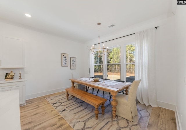 dining space with an inviting chandelier and light hardwood / wood-style flooring