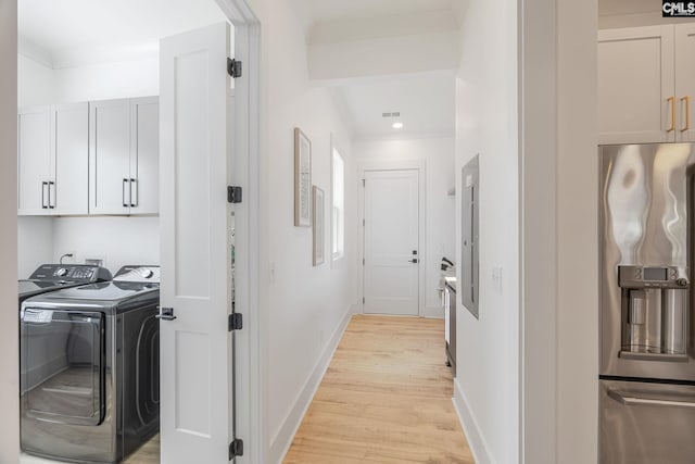 laundry area with cabinets, washer and clothes dryer, and light hardwood / wood-style floors