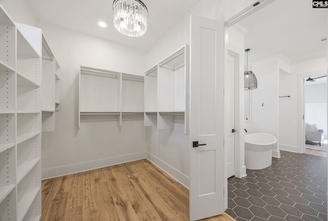 spacious closet with dark hardwood / wood-style floors and a chandelier