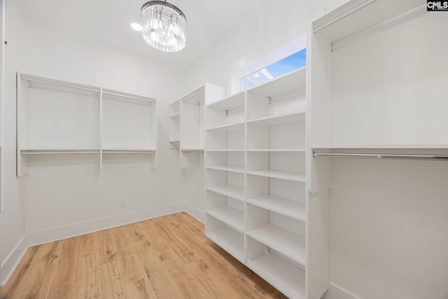 walk in closet featuring light wood-type flooring and a chandelier