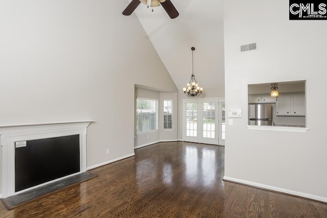 unfurnished living room with high vaulted ceiling, dark hardwood / wood-style flooring, and ceiling fan with notable chandelier