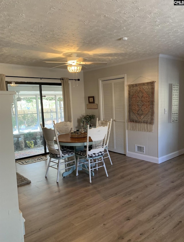 dining room featuring crown molding, hardwood / wood-style flooring, and a textured ceiling