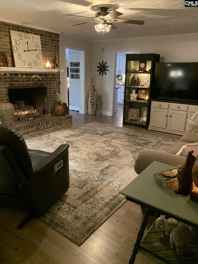 living room with ceiling fan, a textured ceiling, a fireplace, and light hardwood / wood-style floors