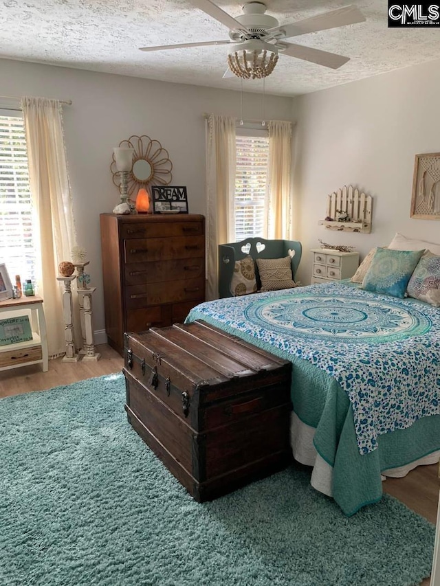 bedroom with ceiling fan, wood-type flooring, and a textured ceiling