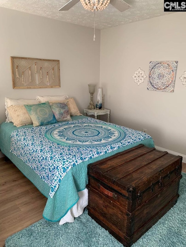 bedroom featuring ceiling fan, hardwood / wood-style flooring, and a textured ceiling