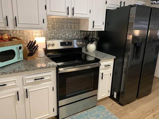 kitchen featuring stainless steel appliances, light stone countertops, decorative backsplash, and white cabinets