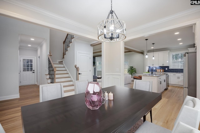 dining room featuring an inviting chandelier, ornamental molding, sink, and light wood-type flooring