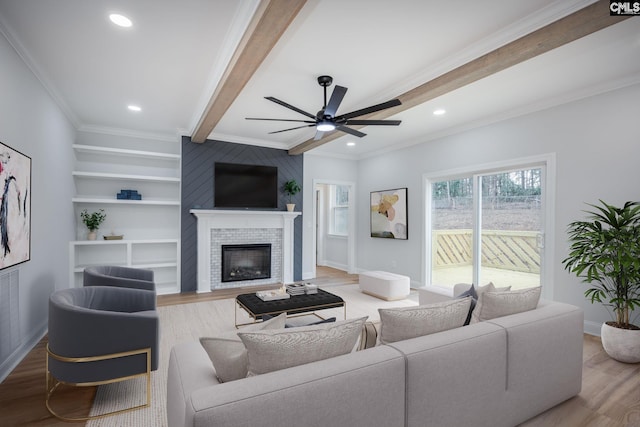 living room with crown molding, wood-type flooring, beam ceiling, and a tile fireplace