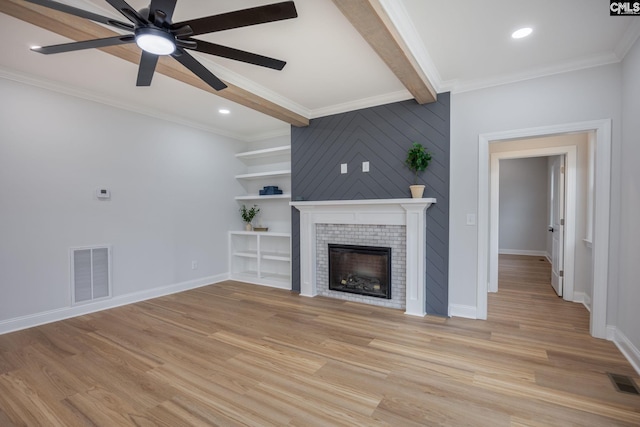 unfurnished living room featuring a tile fireplace, beamed ceiling, ceiling fan, crown molding, and light wood-type flooring