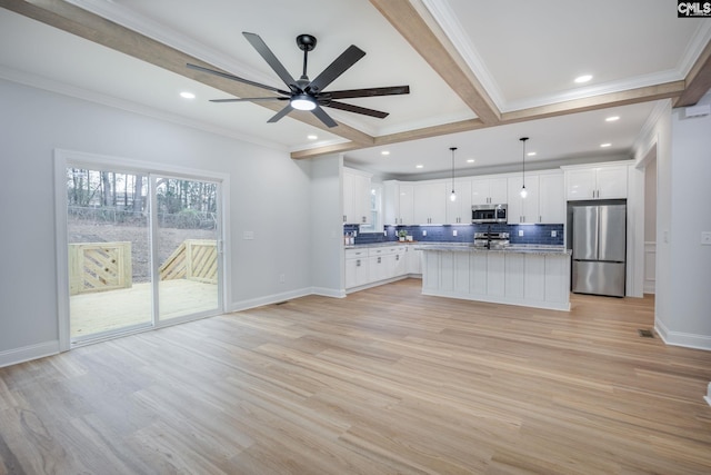 kitchen featuring appliances with stainless steel finishes, a kitchen island, white cabinetry, decorative backsplash, and hanging light fixtures