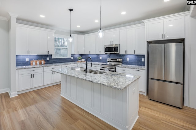 kitchen featuring a kitchen island with sink, decorative light fixtures, stainless steel appliances, and white cabinets