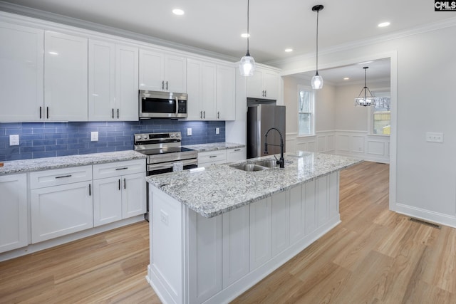 kitchen with stainless steel appliances, sink, a center island with sink, and white cabinets