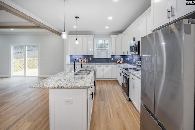 kitchen with sink, hanging light fixtures, an island with sink, stainless steel appliances, and white cabinets