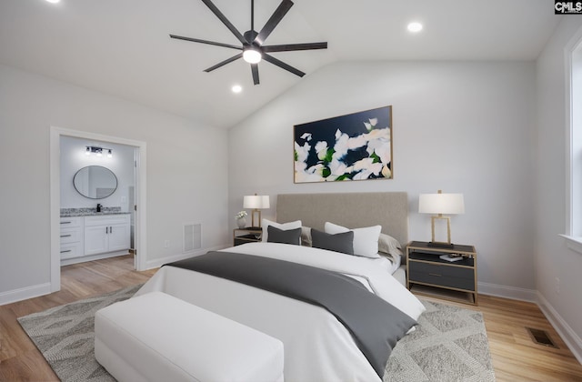 bedroom featuring lofted ceiling, ensuite bathroom, sink, light hardwood / wood-style flooring, and ceiling fan