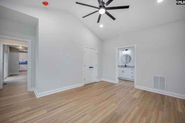 unfurnished bedroom with ensuite bathroom, high vaulted ceiling, ceiling fan, light hardwood / wood-style floors, and a closet