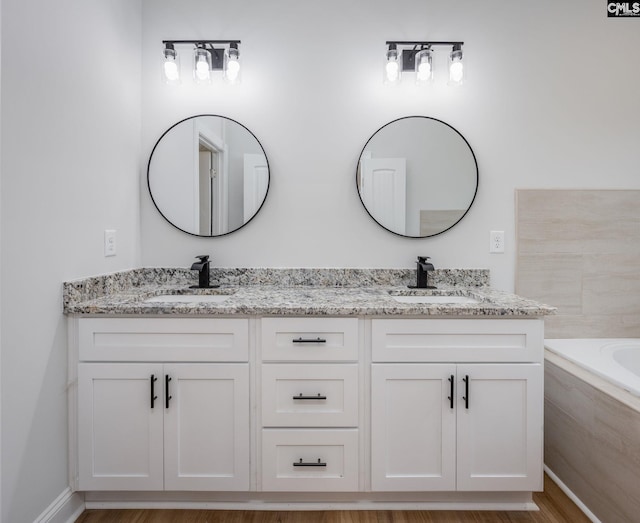 bathroom with tiled tub and vanity