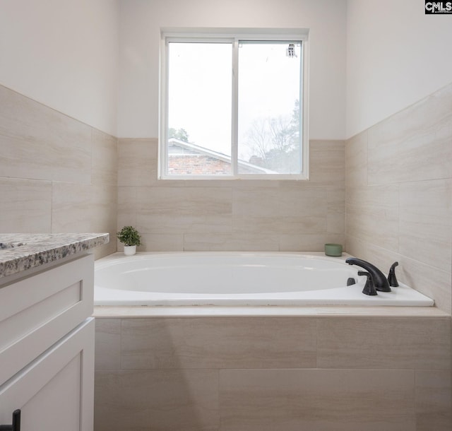 bathroom with vanity and tiled tub