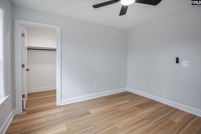 unfurnished bedroom featuring a closet, a walk in closet, ceiling fan, and light hardwood / wood-style flooring