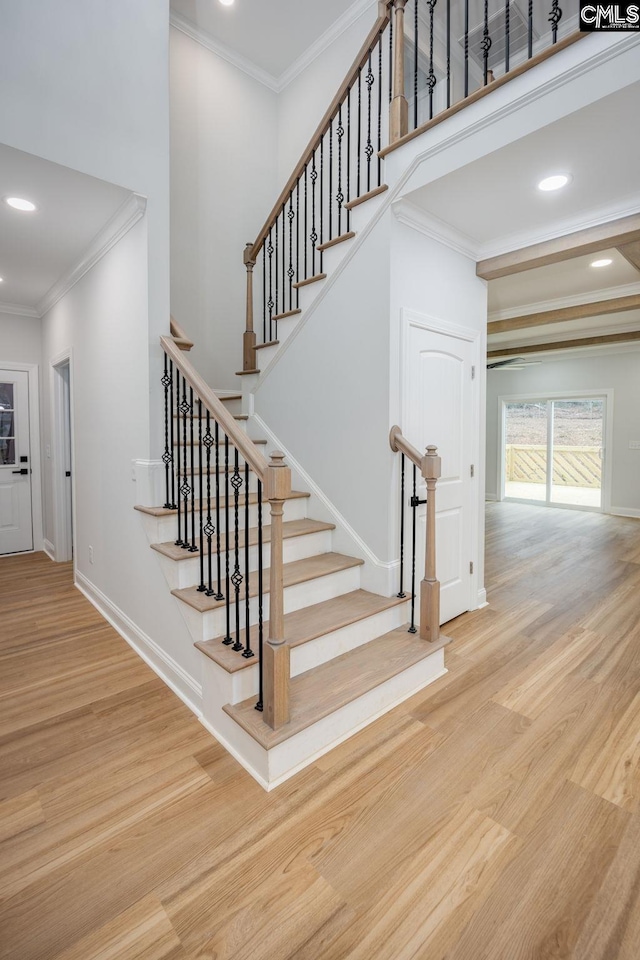 stairs with crown molding, hardwood / wood-style floors, and a high ceiling