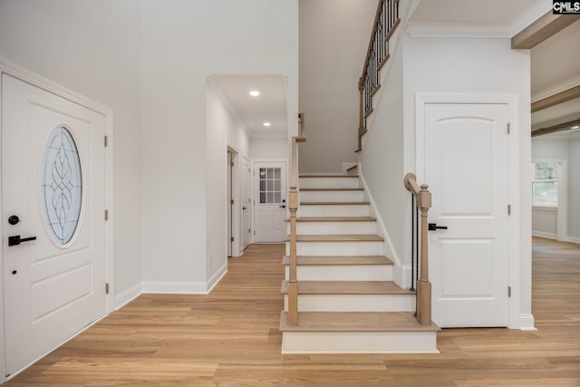 foyer with crown molding and light hardwood / wood-style flooring