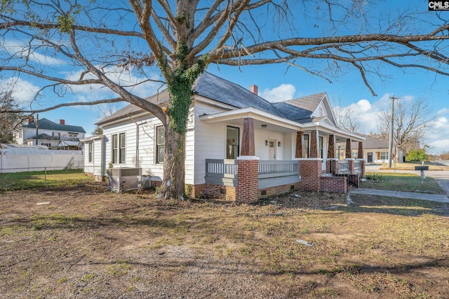 view of side of home with a porch, a yard, and central air condition unit