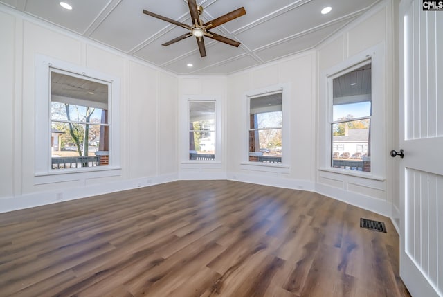 empty room featuring coffered ceiling, plenty of natural light, and dark hardwood / wood-style floors