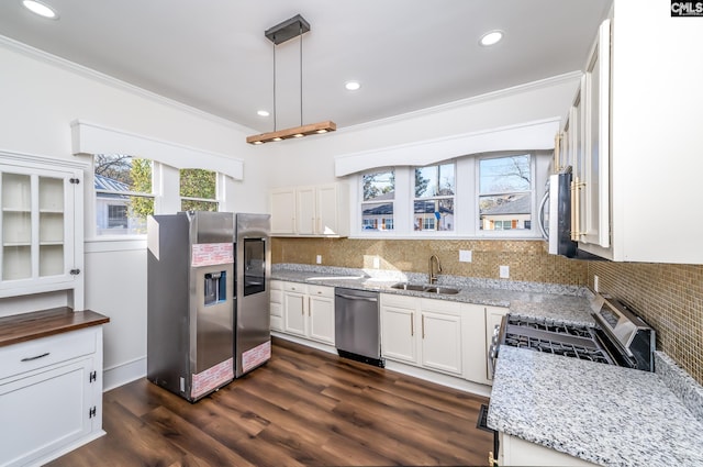 kitchen with sink, white cabinetry, stainless steel appliances, light stone counters, and decorative light fixtures